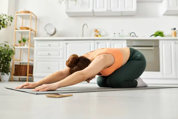 Middle-aged woman gracefully performs yoga pose on floor at home. — Stock Photo