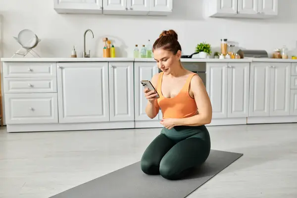 Frau mittleren Alters auf Yogamatte checkt Smartphone. — Stockfoto