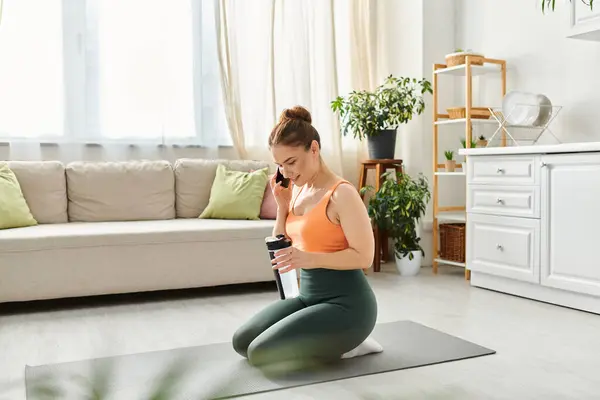 Middle aged woman on yoga mat, conversing on cellphone. — Stock Photo