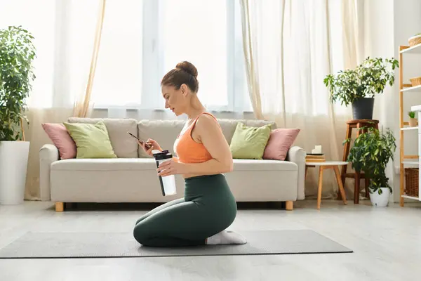 Mujer de mediana edad meditando serenamente sobre una esterilla de yoga en una acogedora sala de estar. - foto de stock