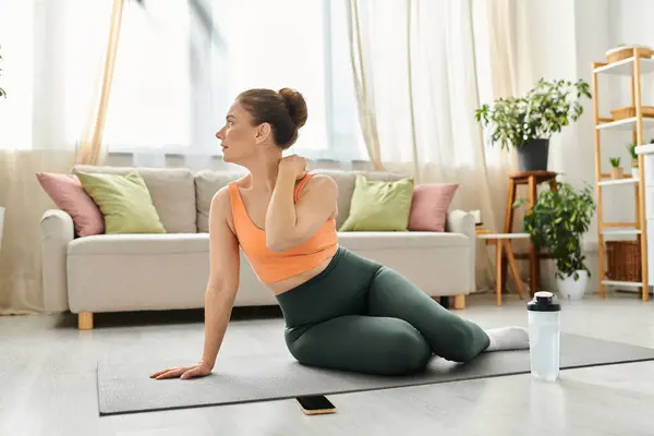Donna di mezza età colpisce con grazia una posa yoga nel suo accogliente soggiorno. — Foto stock