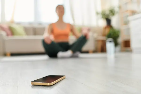 Женщина средних лет сидит на полу, сосредоточенная на экране своего мобильного телефона. — стоковое фото