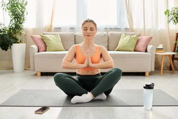 Frau mittleren Alters praktiziert Yoga vor einem Sofa. — Stockfoto