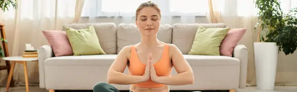 Femme d'âge moyen effectue gracieusement le yoga devant un canapé. — Photo de stock