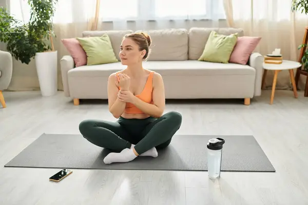 Mujer de mediana edad practicando yoga en una estera en su sala de estar. - foto de stock