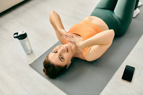 Femme d'âge moyen pratiquant la pose de yoga sur tapis à la maison. — Photo de stock