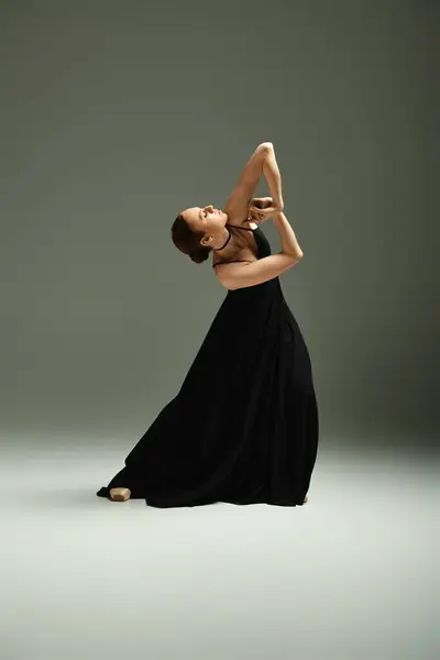 Young beautiful ballerina in a black dress strikes a dance pose. — Stock Photo