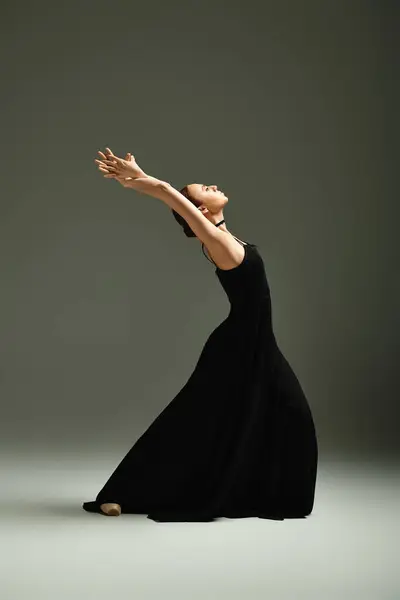 Una giovane bella ballerina colpisce con grazia una posa da ballo in un vestito nero. — Foto stock