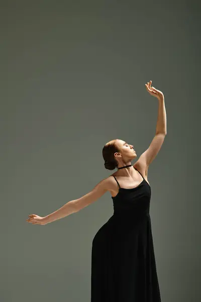 Eine junge, schöne Ballerina tanzt anmutig in einem schwarzen Kleid. — Stock Photo