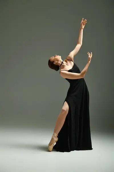 A young, beautiful ballerina in a black dress gracefully dances with skill and precision. — Stock Photo