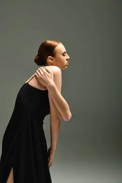 A young, beautiful ballerina in a black dress strikes a pose for a photograph. — Stock Photo