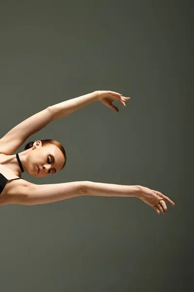 Talented young ballerina gracefully performs a stunning trick in a black leotard. — Stock Photo