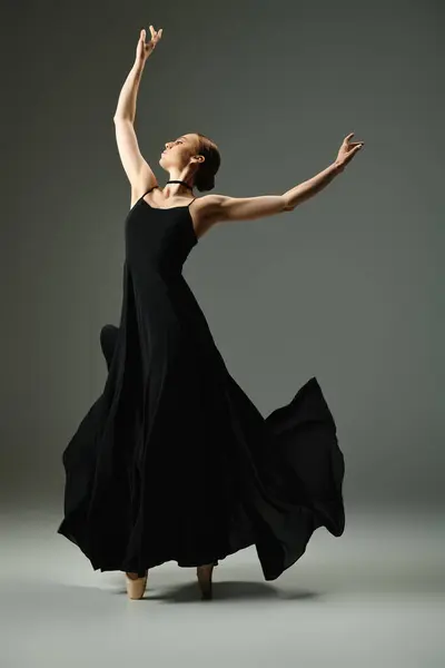 Молода, талановита балерина витончено танцює в чорній сукні, що тече. — стокове фото