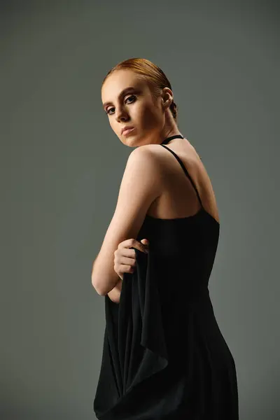 A young ballerina in a sleek black dress strikes a pose for a photograph. — Stock Photo