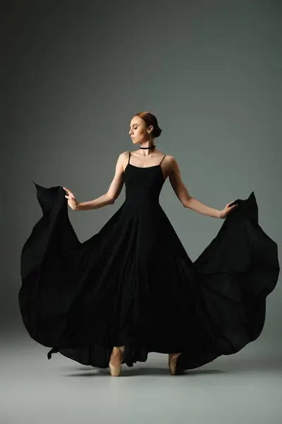 Молода балерина в чорній сукні танцює витончено. — стокове фото