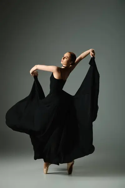 Uma bailarina jovem e bonita em um vestido preto dança graciosamente. — Fotografia de Stock
