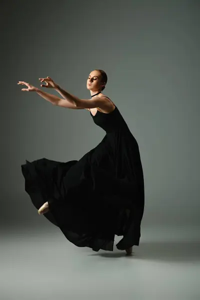 Молода, красива балерина в чорній сукні танцює витончено. — стокове фото
