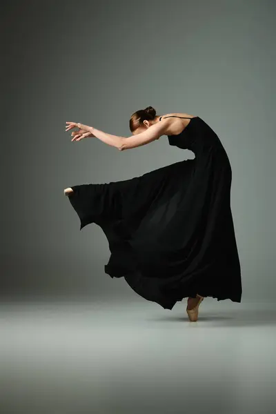 Une jeune, belle ballerine en robe noire dansant gracieusement. — Photo de stock