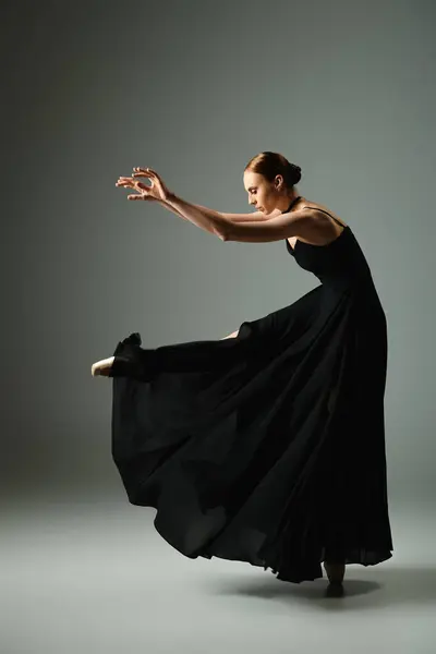 Молодая, красивая балерина в черном платье изящно танцует. — стоковое фото