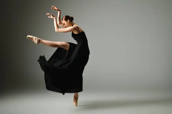Uma bailarina jovem e bonita em um vestido preto dança elegantemente. — Fotografia de Stock