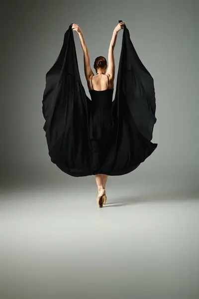 Une jeune et belle ballerine en robe noire danse gracieusement. — Photo de stock