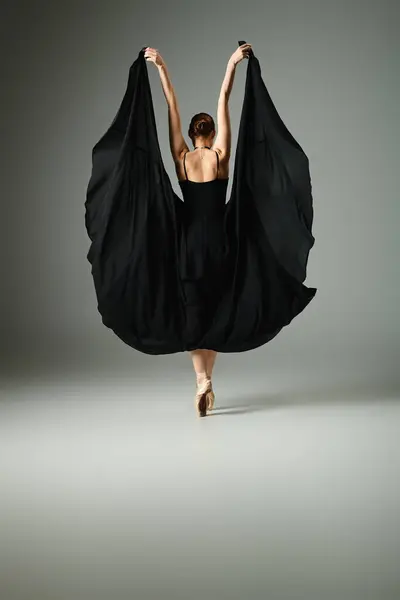 A young, beautiful ballerina in a black dress dances gracefully. — Stock Photo