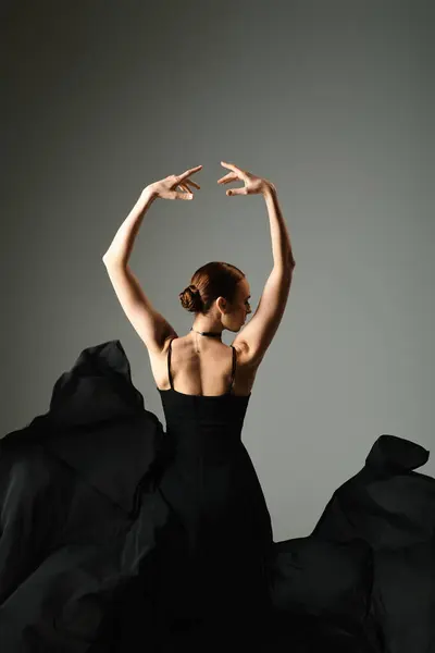 Молода балерина в чорній сукні витончено танцює руками в повітрі. — стокове фото