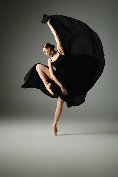 Eine junge schöne Ballerina in einem schwarzen Kleid tanzt anmutig. — Stock Photo