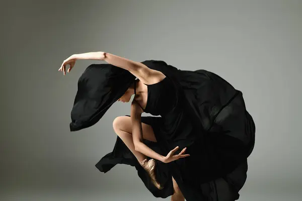 Une jeune et belle ballerine en robe noire danse gracieusement. — Photo de stock