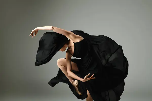 A young, beautiful ballerina in a black dress dances gracefully. — Stock Photo