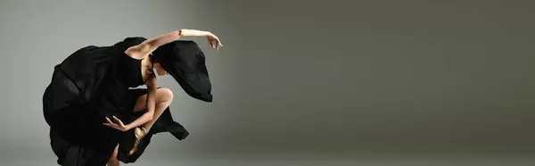 Una joven y hermosa bailarina baila elegantemente en un elegante vestido negro. - foto de stock