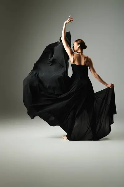 Молода, красива балерина в чорній сукні танцює витончено на сцені. — стокове фото