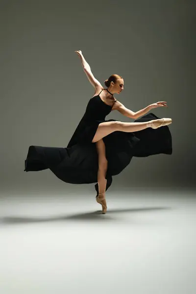 Joven, hermosa bailarina baila con gracia en un vestido negro. - foto de stock