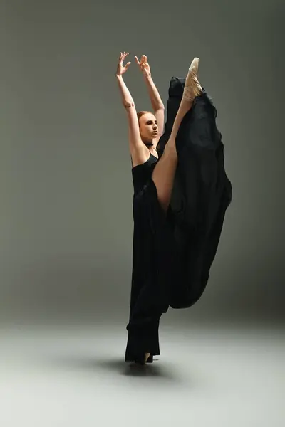 Una bailarina joven y hermosa en un vestido negro bailando con gracia y habilidad. - foto de stock
