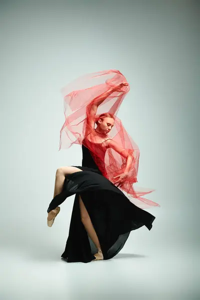 A young woman in a black dress and a red scarf gracefully dances. — Stock Photo