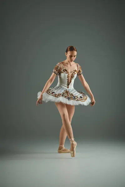 A young, beautiful ballerina gracefully strikes a pose in a white tutu. — Stock Photo