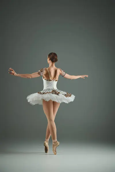 Young ballerina in white tutu and leotard dancing gracefully on stage. — Stock Photo
