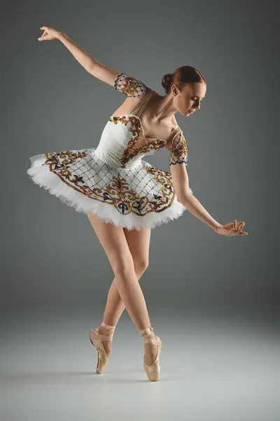 Una bailarina joven y talentosa baila con gracia en un tutú blanco con adornos de oro. - foto de stock