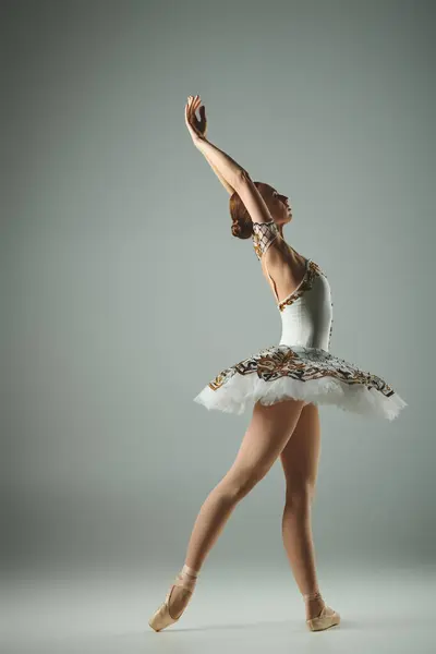 Молодая, красивая балерина, исполняющая пируэт в белой пачке и элегантных золотых туфлях. — стоковое фото