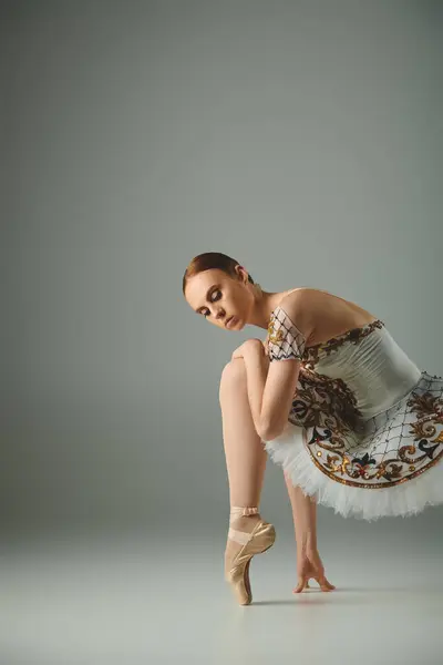 Eine junge, schöne Ballerina in einem weißen Kleid beugt sich anmutig nach unten. — Stock Photo