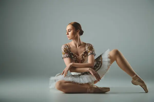 Junge Ballerina sitzt in Ballettkleidung auf dem Boden und strahlt Anmut und Eleganz aus. — Stock Photo