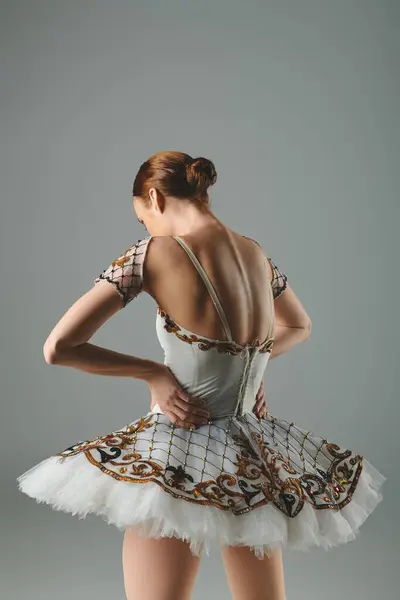 Молода балерина витончено виступає в білій і золотій сукні. — стокове фото