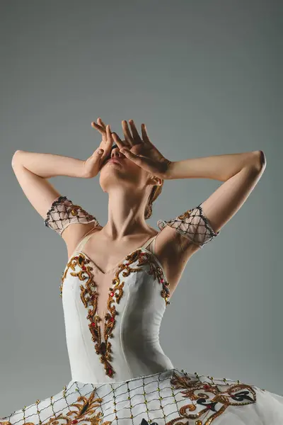 Молодая, красивая балерина в белом и золотом платье танцует с элегантностью и страстью. — стоковое фото