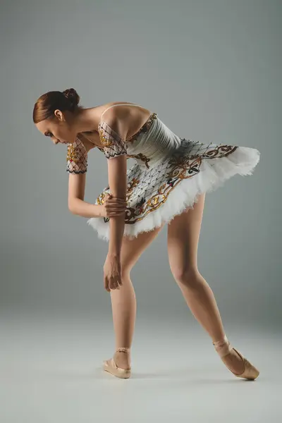 Молода, красива балерина танцює витончено в приголомшливій білій і золотій сукні. — стокове фото