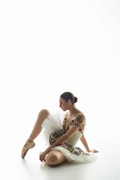 Una giovane bella ballerina siede sul pavimento con le gambe incrociate. — Foto stock