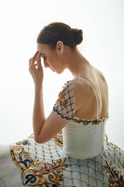 A graceful ballerina in a flowing white dress sits elegantly. — Stock Photo
