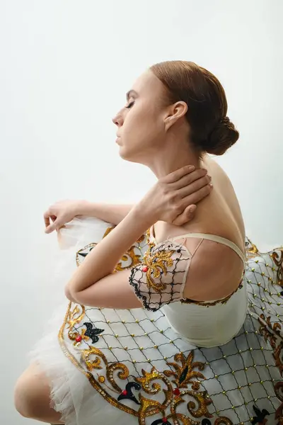 Молода жінка в білій і золотій сукні витончено тримає руки на грудях. — стокове фото