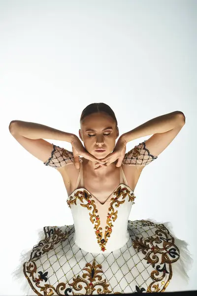 Talentierte Ballerina in einem atemberaubenden weiß-goldenen Outfit, die anmutig auf der Bühne tanzt. — Stockfoto