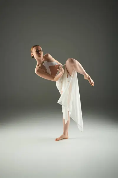 Jeune ballerine dans une robe blanche fluide effectuant un stand de main avec grâce et élégance. — Photo de stock