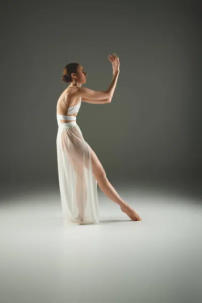 Молода балерина витончено танцює в білій сукні. — стокове фото